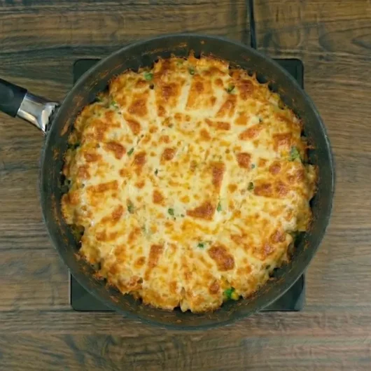 Arroz cremoso na frigideira servido com queijo derretido