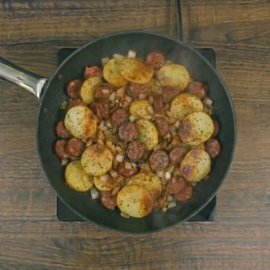 Batata com linguiça na frigideira dourada e servida quente
