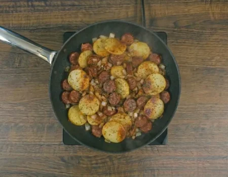 Batata com linguiça na frigideira dourada e servida quente