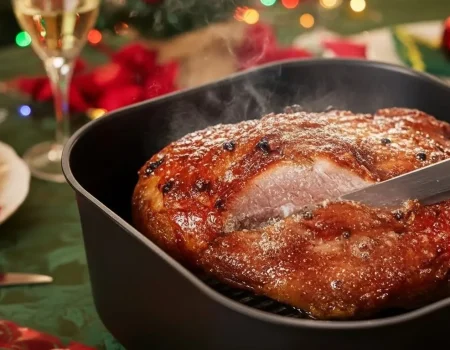 Pernil fatiado servido na mesa de ceia de Natal com decoração festiva.