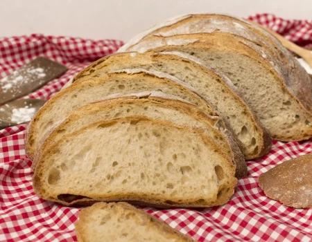 pão caseiro fatiado sobre uma mesa com uma toalha quadriculada vermelha e branca